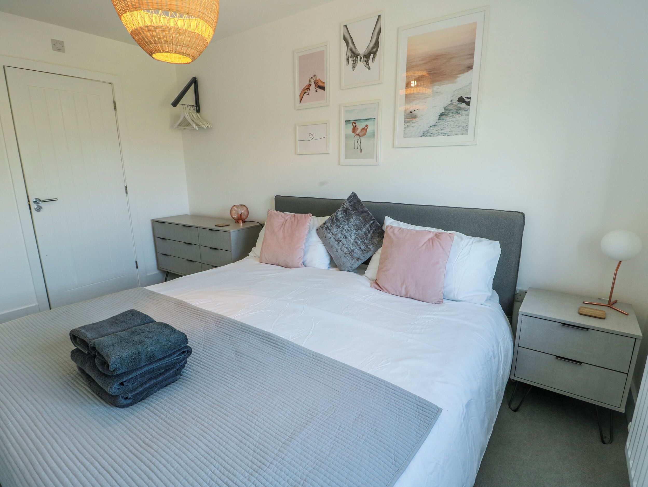 A neatly arranged bedroom with a bed, bedside tables, a wardrobe, and wall art.