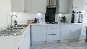 A modern kitchen with a gas stove, stainless steel appliances, and white cabinetry. - Dune Retreat (Ty Croes)