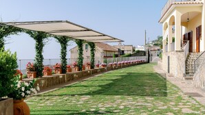 A pathway lined with potted plants and a building with a stone facade and a balcony. - Apt Anna in Villa Laura near Ravello  (scala)