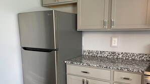 Una cocina con refrigerador de acero inoxidable, armarios de madera y encimera de granito.