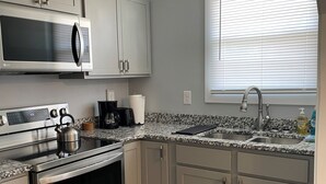 Una cocina moderna con electrodomésticos de acero inoxidable, encimera de granito y armarios color gris claro.