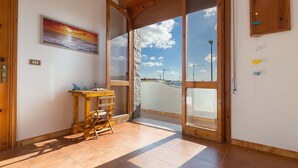 A room with a wooden table, chairs, a painting, and a view of the sea through a glass door. - 2191 Appartamento Blue Dreams by Barbarhouse (Melendugno)