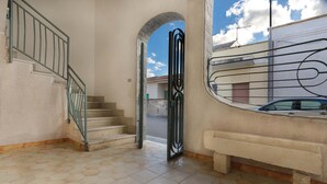 A staircase with a metal railing, a bench, and a view of the street through an open door. - 2191 Appartamento Blue Dreams by Barbarhouse (Melendugno)