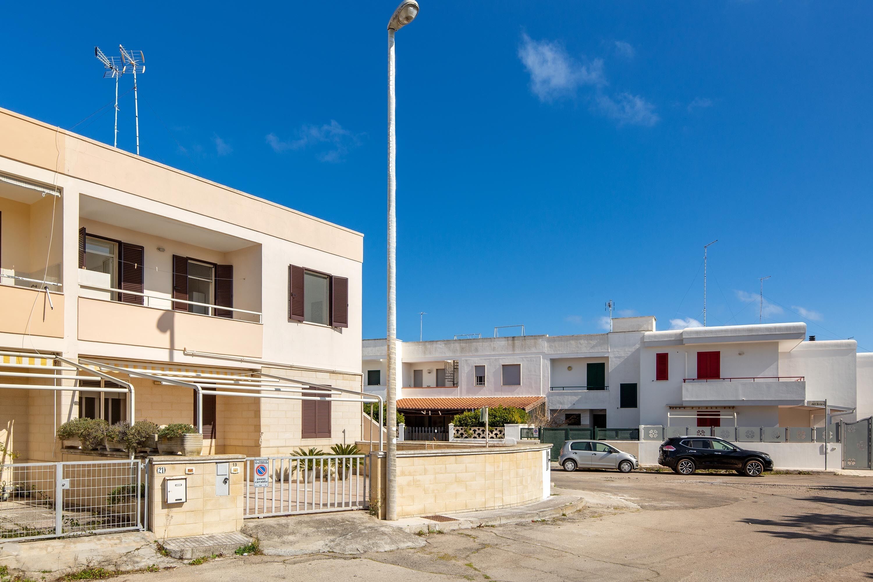 A residential area with modern buildings, a gated entrance, and a clear blue sky.
