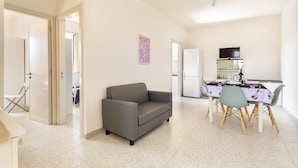A compact living space with a sofa, dining table, chairs, and a refrigerator. - 2226 Carlotta`s House by Barbarhouse (Melendugno)