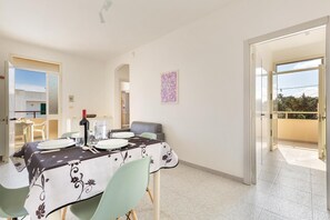 A dining area with a table set for four, a chair, a wine bottle, and a painting on the wall. - 2226 Carlotta`s House by Barbarhouse (Melendugno)
