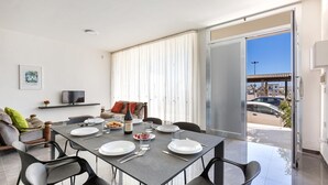 A dining area with a table set for four, a sofa, and a TV on the wall. - 2178 Appartamento Negroamaro by Barbarhouse (Leverano)