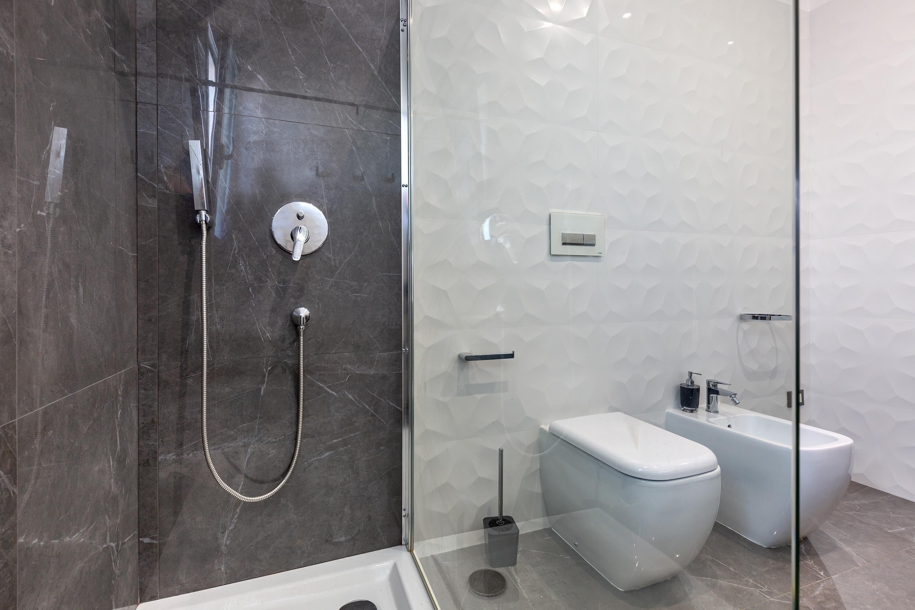 Un baño moderno con ducha vidriada, inodoro y bidé.