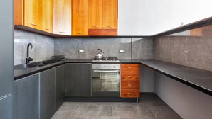A compact kitchen with wooden upper cabinets, a stainless steel oven, and a black countertop. - 2178 Appartamento Negroamaro by Barbarhouse (Leverano)