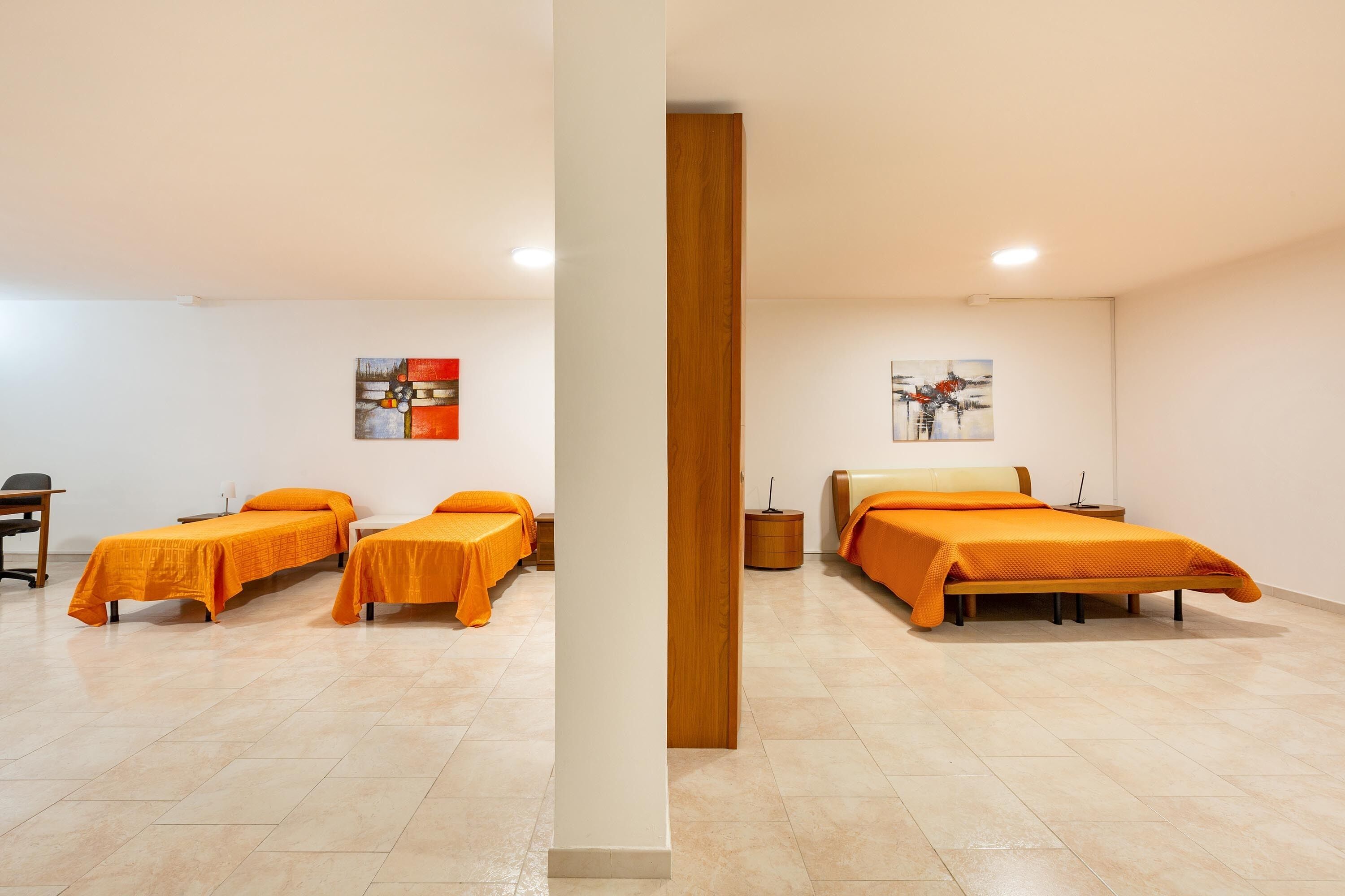 Een hotelkamer met twee eenpersoonsbedden, een houten pilaar en kunst aan de muren.