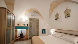 Une chambre à coucher comprenant un lit, une armoire en bois, une porte en arc de cercle et des appliques murales décoratives.
