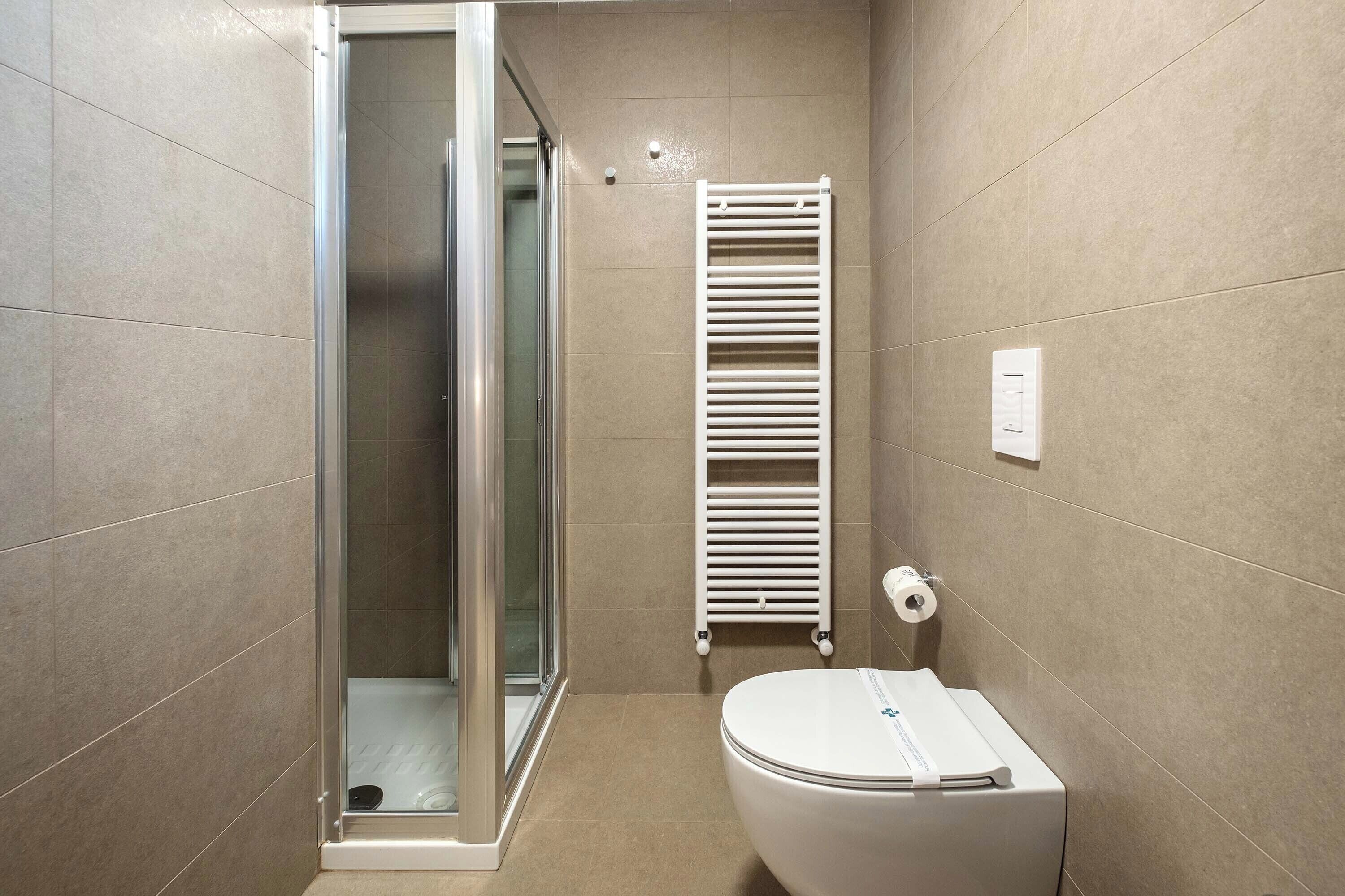 A bathroom with a glass-enclosed shower, a white toilet, and a towel rack.