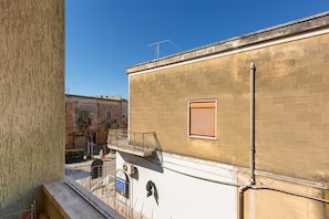 A building with a brick facade, a window with a shutter, and a metal railing on the upper floor. - 2253 Casa Jacopo (Mesagne)
