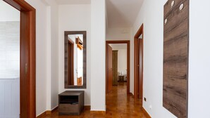 A hallway with a wooden floor, a mirror, a small cabinet, and a wall-mounted panel. - 2253 Casa Jacopo (Mesagne)