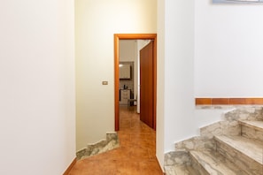 A hallway leading to a kitchen with a stone staircase. - 2253 Casa Jacopo (Mesagne)