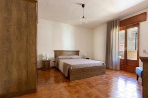 A bedroom with a wooden bed, a nightstand, a lamp, and a view through a door. - 2253 Casa Jacopo (Mesagne)