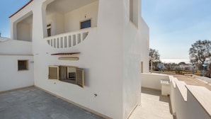 A two-story building with a balcony, a small window, and a door.