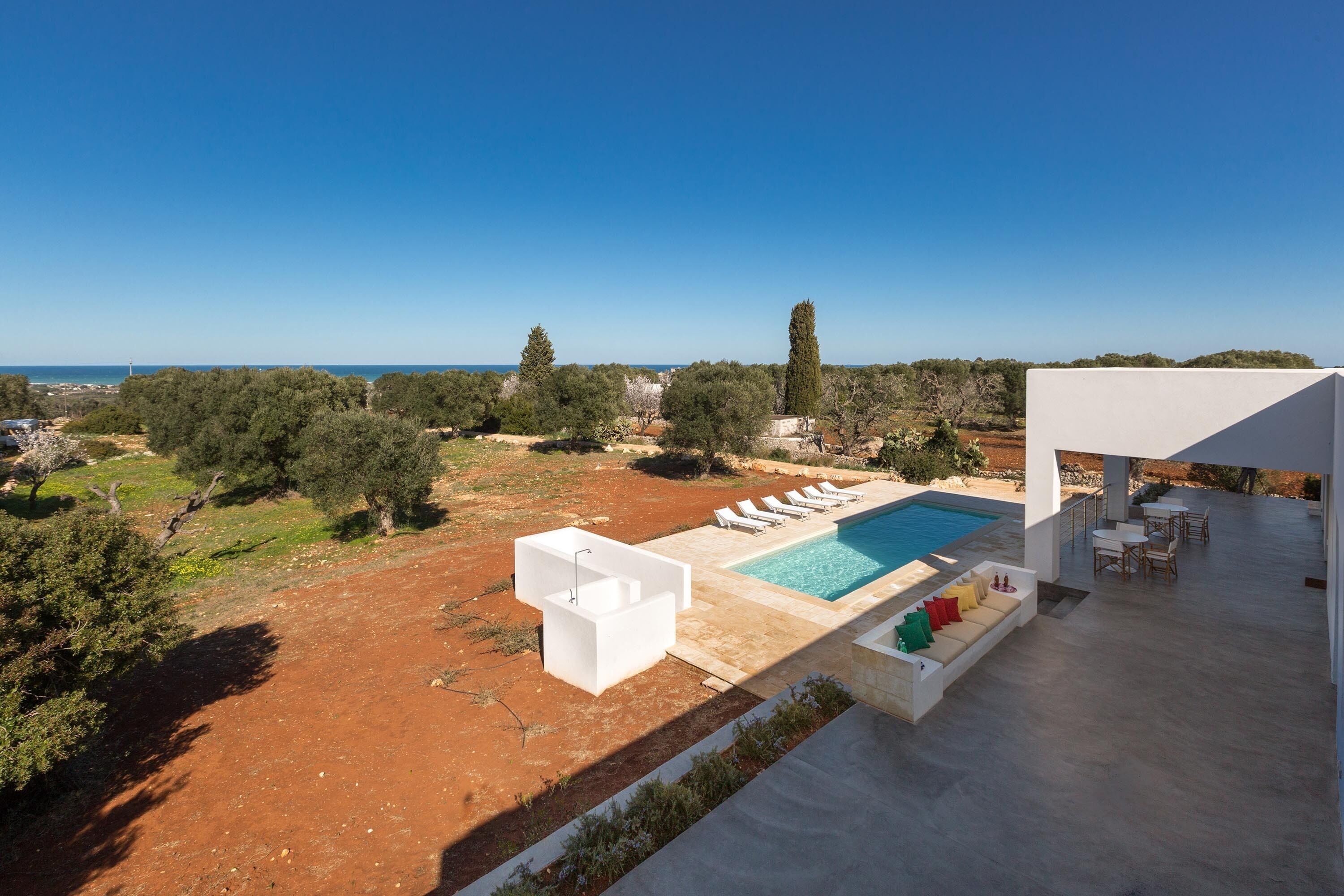 Una villa moderna con piscina, mobiliario exterior y vistas al mar.