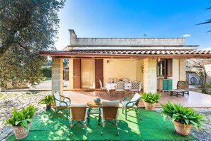 Eine Terrasse mit Gartenmöbeln, einer Pergola und Kübelpflanzen.