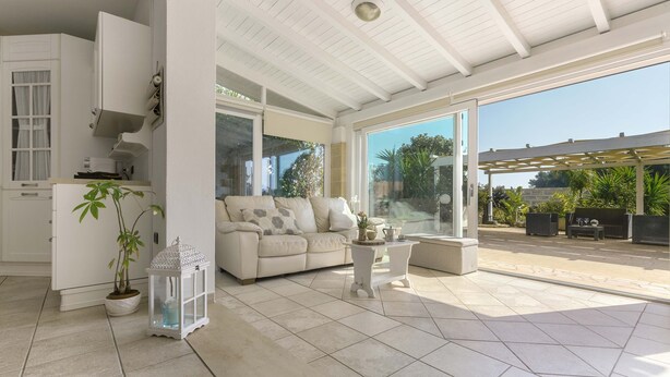 A spacious living area with a white sofa, a small table, and a potted plant. - 2210 Villa Sergi by Perle di Puglia (Gagliano del Capo)
