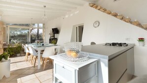 A modern kitchen with a central island, white cabinetry, and a stone accent wall. - 2210 Villa Sergi by Perle di Puglia (Gagliano del Capo)