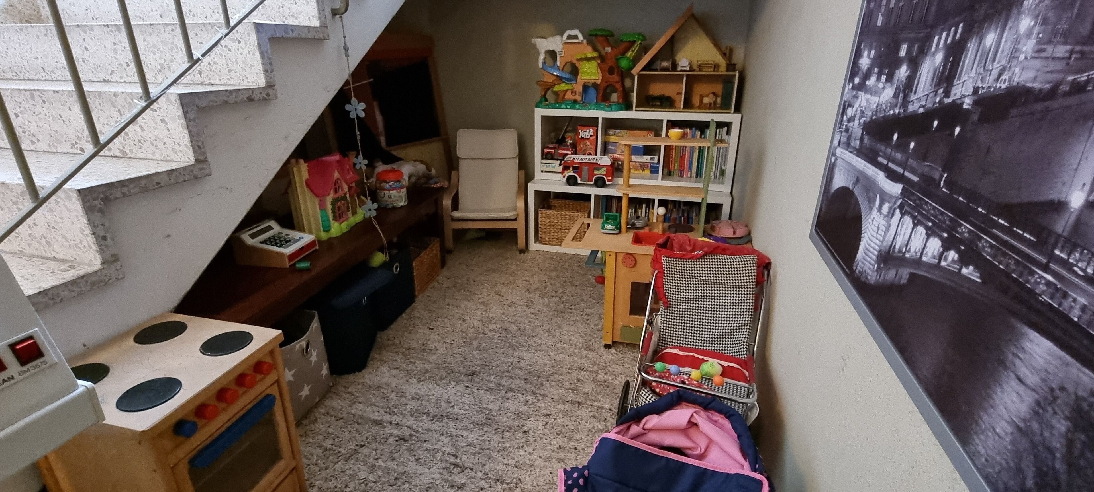 A child's playroom with a toy kitchen, a bookshelf, and a toy car.
