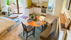 A compact living space with a kitchenette, a dining area, and a bedroom. - Souterrainwohnung mit Großem Garten (Kassel)