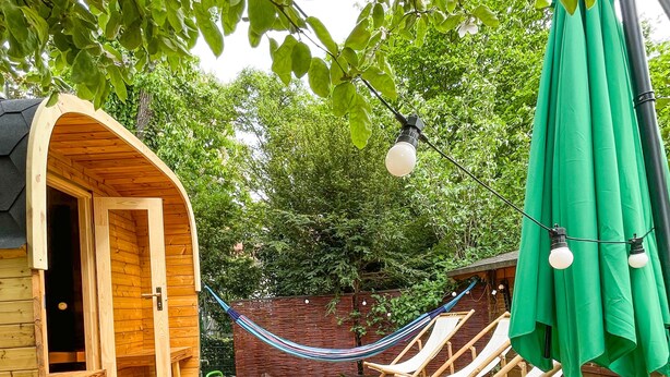A wooden deck with a hammock, lounge chairs, and a small table with fruits. - Souterrainwohnung mit Großem Garten (Kassel)