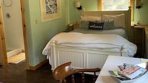 A bedroom with a bed, a ceiling fan, a window, a bedside table, and a chair.