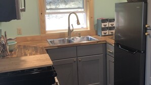 A compact kitchen with a sink, a refrigerator, and wooden cabinets.