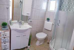 A bathroom with a white sink, toilet, and shower. There are plants on the sink and a towel rack above the toilet. - A1- apt With Terrace, Just 3 min Walk to the Beach (Rogoznica)