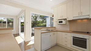 Una cocina moderna con armarios blancos, microondas integrado y lavavajillas.