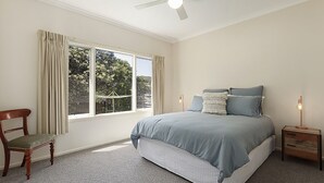 Un dormitorio con una cama grande, una silla, una mesita de noche y un ventilador de techo.