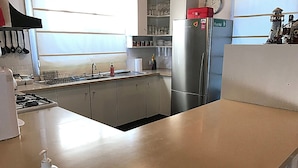 Eine Küche mit einem Edelstahl-Kühlschrank, einer Spüle und einer Arbeitsplatte mit einer Handdesinfektionsmittel-Flasche.
