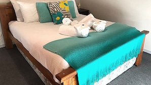 Ein Bett mit einem türkisfarbenen Überwurf, Kissen und aufgerollten Handtüchern.