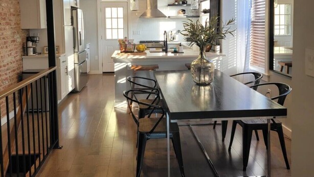 A modern kitchen with a central island, pendant lighting, and a view to the dining area.