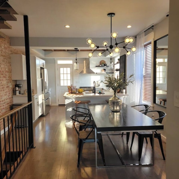A modern kitchen with a central island, pendant lighting, and a view to the dining area.