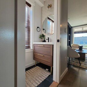 Ein modernes Badezimmer mit Waschtisch, Spiegel und Fenster mit Jalousien.