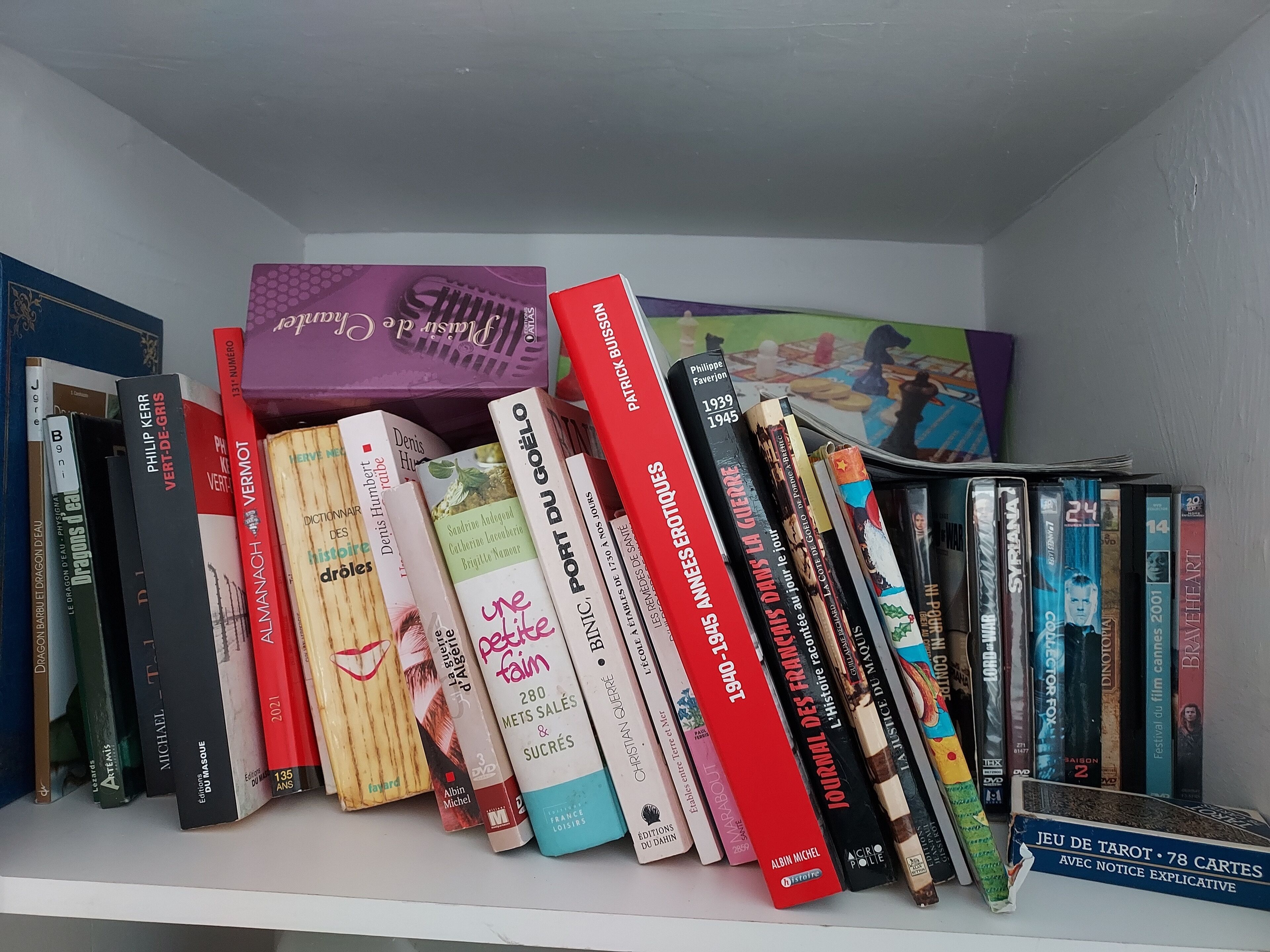 En reol fyldt med diverse bøger og DVD'er.