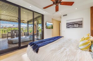 Ein Schlafzimmer mit einem großen Bett, einem Deckenventilator und Blick auf einen Balkon mit Gartenmöbeln.