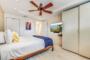 Ein Schlafzimmer mit Bett, Deckenventilator, Fernseher und Kleiderschrank.