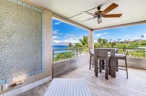Ein Balkon mit Blick auf das Meer, ein Deckenventilator und ein Tisch mit Stühlen.