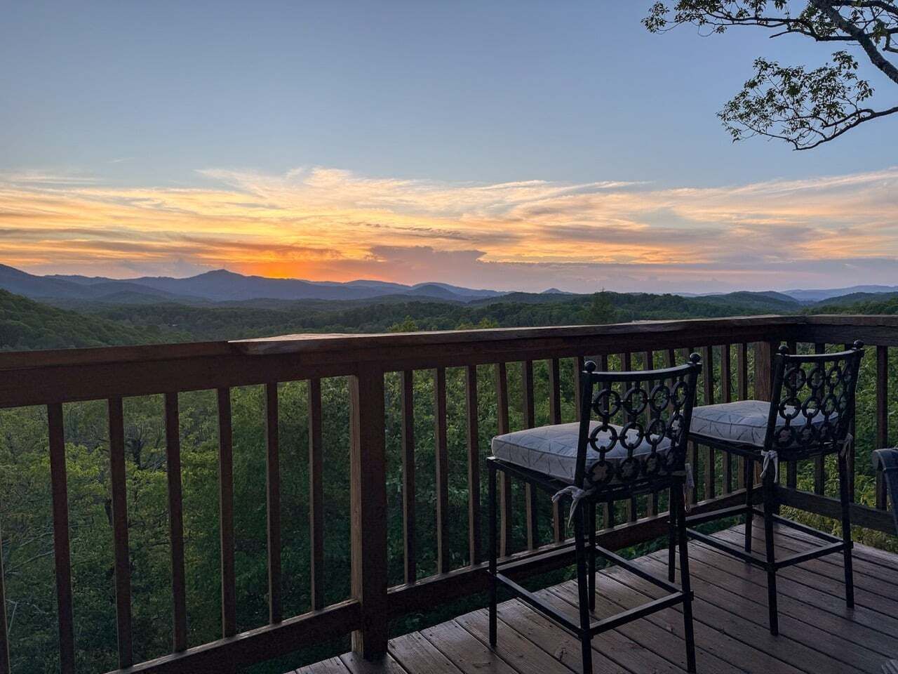 Eine Terrasse mit Blick auf einen Sonnenuntergang über einer Berglandschaft.
