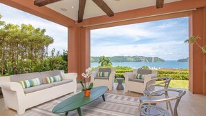 A spacious outdoor seating area with a view of the sea, featuring a sofa, chairs, and a coffee table. - Ocean View, Modern Luxury w/Jacuzzi & access to all amenities! (Puntarenas)