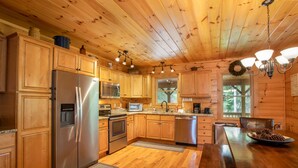 A wooden cabin kitchen with a refrigerator, stove, microwave, and dishwasher. - Spacious Log Home with EV Charger (Vilas)