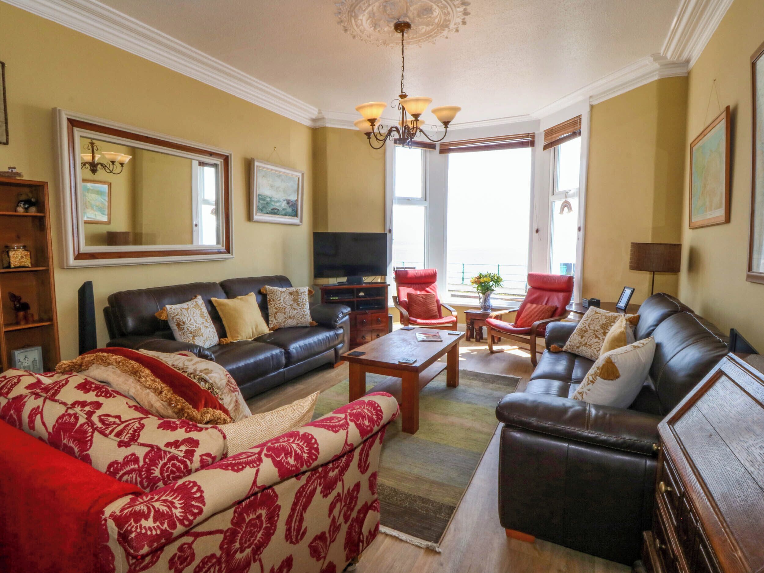 Een woonkamer met een bank, fauteuils, een salontafel en een televisie.