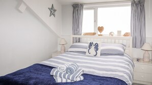 Une chambre à coucher bien rangée, avec un lit, des tables de chevet, une fenêtre avec des rideaux et une décoration en forme d’étoile sur le mur.
