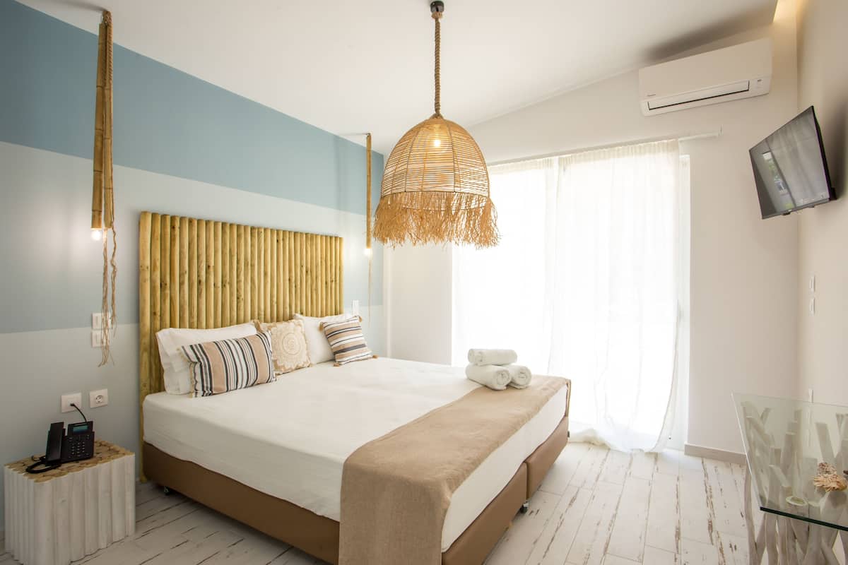 A modern bedroom with a large bed, a hanging light fixture, a bedside telephone, and a television on the wall.