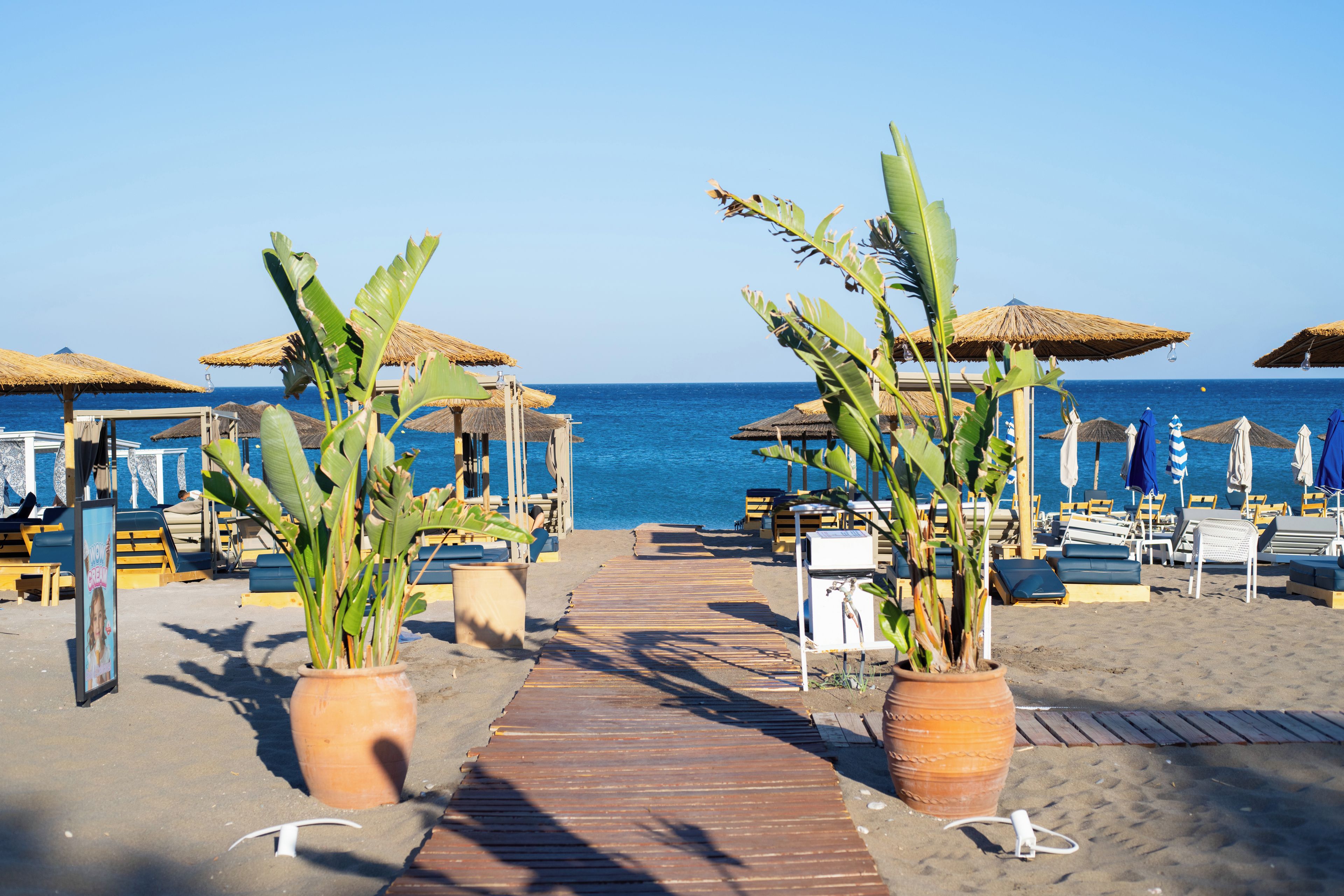 A beachside walkway leading to beach chairs and umbrellas, with a clear view of the sea.