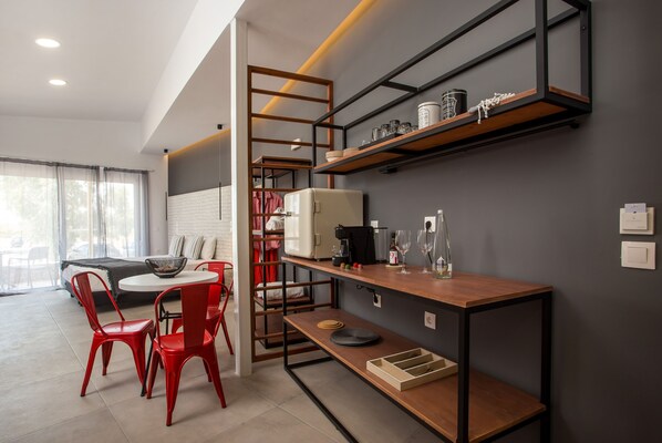 A modern kitchen with a wooden table, red chairs, and built-in shelves. - Marini Seaside (Rhodes)